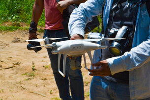 Eine Flug-Drohne wird von 2 Händen gehalten. 