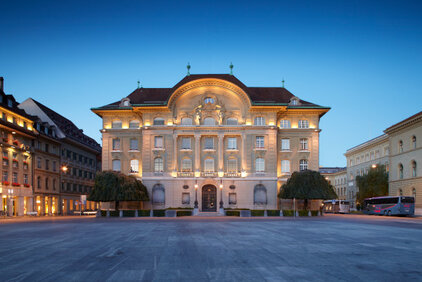 Fassade der Nationalbank im Abendlicht, beleuchtet.