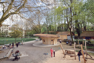 Blick auf Spielplatz, Holzpavillon, Bäume und Menschen.